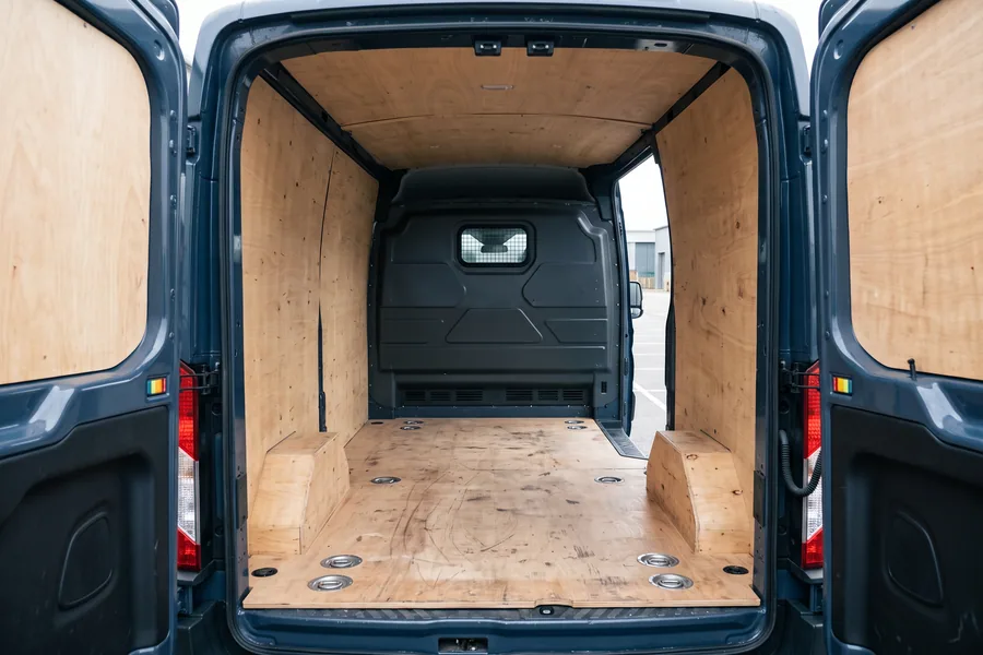 Empty ply lined load bay of a medium van seen through the open rear doors